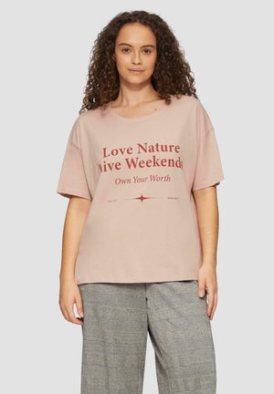 T-shirt en coton rose clair à manches courtes, avec un design graphique en texte rouge audacieux. Coupe décontractée et décolleté rond.
