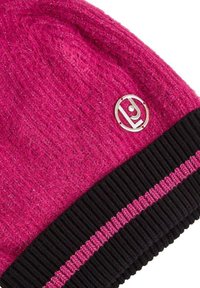 Berretto lavorato a maglia in fucsia vivace con un risvolto nero a coste, caratterizzato da un accento di logo metallico e una sottile luminosità su tutto il tessuto.