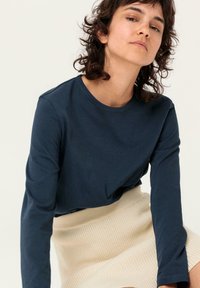 Navy Langarmshirt aus weichem Baumwollstoff, mit rundem Ausschnitt und lässiger Passform, kombiniert mit einem cremefarbenen gerippten Strickrock.