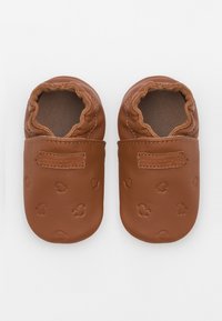 Pantofii de bebeluși din piele maro, cu deschideri elastice, embossati cu modele mici de urme de labe, cu o suprafață texturată și căptușeală moale.