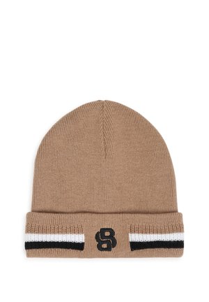 Bonnet en tricot beige avec revers plié, présentant des rayures noires et blanches et une lettre S noire brodée sur le revers avant.