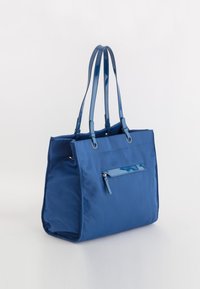 Blauwe nylon draagtas met glanzende blauwe patenten lederen accenten, twee lange handvatten en een ritszak aan de voorkant. Gladde textuur.