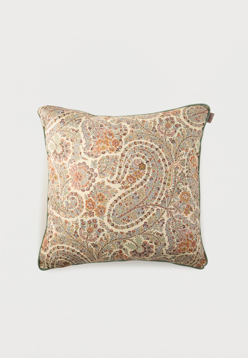 Coussin carré décoratif avec fond beige et motifs floraux paisley complexes en orange, marron et vert, avec un passepoil vert le long des bords.
