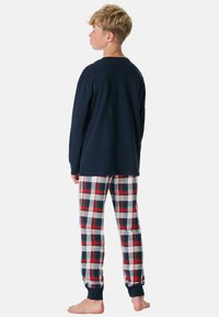 Marineblaues Langarmshirt kombiniert mit karierten Schlafanzughosen in Rot, Weiß und Blau. Das Shirt hat gerippte Bündchen; die Hose verfügt über einen elastischen Bund.