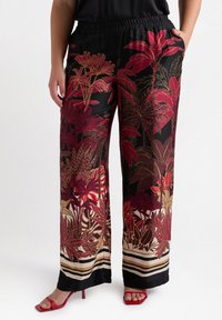 Wide-leg patterned pants in black, featuring red and gold floral designs. Elastic waistband with side pockets. Accented with horizontal stripes at the hem.