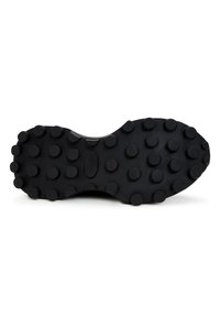 Semelle de chaussure noire avec des crampons circulaires en relief uniformément répartis pour la traction, vue de dessous sur fond blanc.