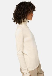 Cremfarbener Rollkragensweater aus weichem Stoff, mit langen Ärmeln und einer figurbetonten Silhouette. Einfaches Design ohne sichtbare Muster oder Akzente.
