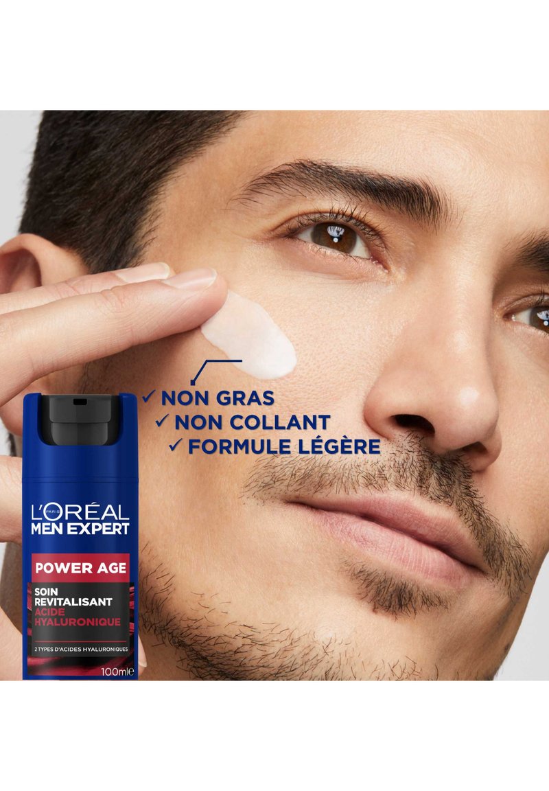 Le soin hydratant Power Age de L'Oréal Men Expert dans un flacon pompe bleu, avec une texture de crème blanche appliquée sur la peau du visage de la personne.