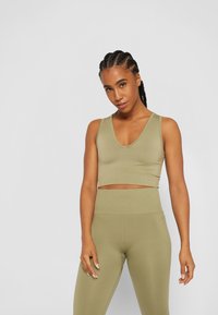 Top de desporto em verde-oliva, cropped, com decote em V e textura canelada, combinado com leggings de cintura alta a condizer. Tecido suave e design ajustado.