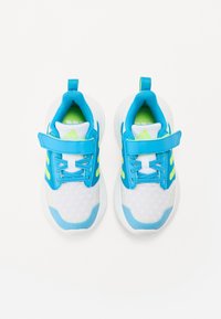 Des chaussures de sport bleu et blanc avec une tige en mesh, fermeture par bande, et des accents verts vif. Comprend une semelle rembourrée et des détails texturés.