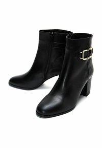 Bottines en cuir noir avec une texture lisse, bout pointu, talon chunky haut, fermeture éclair sur le côté et accent de boucle dorée sur le côté extérieur.
