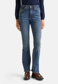 Jeans de mezclilla azul con una cintura ajustada, diseño de pierna recta y costuras a contraste. Presentan bolsillos frontales y un sutil desgaste en las rodillas.