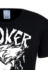 Black cotton t-shirt featuring a large white graphic print of text "JOKER" and a character with spiky hair. Round neckline, short sleeves.