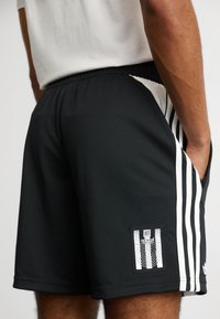 adidas Originals ADIDAS NTS RADIO ALLOVER PRINTED SUPERSTAR TRACK PANTS - Teplákové kalhoty - black