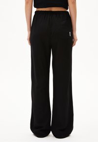 Svarta vida byxor med elastisk midja och bakficka, som har en jämn textur och lös passform.