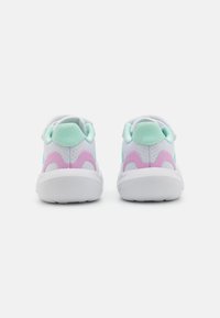 Baskets blanches de sport avec une tige en maille texturée, présentant des accents vert menthe et rose sur les côtés et le talon, ainsi qu'une semelle en caoutchouc blanche.