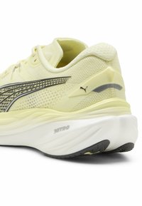 Ljust gula löparskor med överdel i mesh, elegant design och en dämpad sula med svart gummikänga och reflexdetaljer.