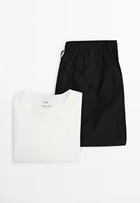 T-shirt bianca in cotone con scollo rotondo accanto a pantaloni corti neri leggeri con vita elasticizzata e cordino.
