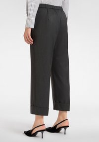 Donkergrijze broek met een rechte snit, voorzien van een opgerolde zoom bij de enkel en een gladde textuur. Draag met zwarte slingback hakken.