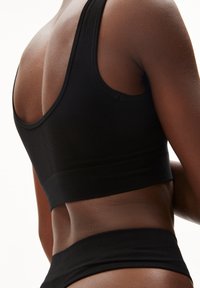 Zwarte atletische tanktop met een racerback-ontwerp. Gemaakt van glad materiaal met getextureerde accenten langs de schouders en de onderste band.