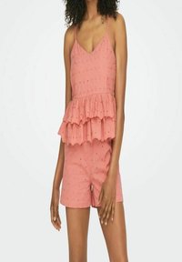 Peplum top og shorts sæt i koralfarvet stof, med et lagdelt flæse-design, tynde stropper og subtile teksturerede detaljer throughout.
