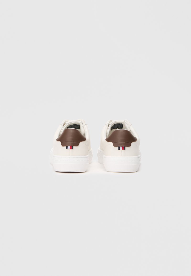White sneakers with brown leather heel accents, featuring a small tricolor stripe design. Smooth material with a minimalist design.