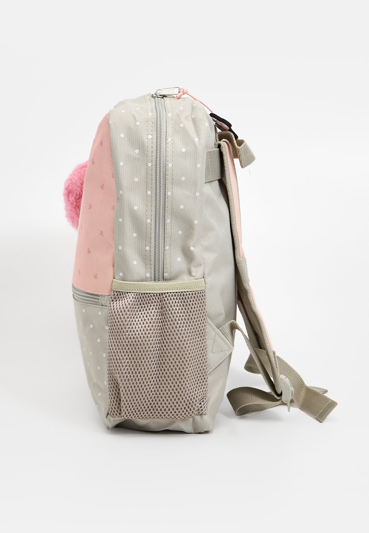 Mochila liviana de tela rosa y beige, con un patrón de puntos, cierre de cremallera, bolsillo de malla lateral y un pompón rosa adjunto.