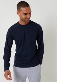 Granatowa koszula z długim rękawem z oddychającego materiału, z rękawami raglanowymi, z subtelnym logo na klatce piersiowej i pasującymi spodniami w paski.