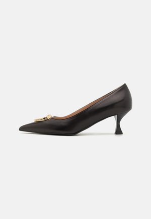 Black leather pointed-toe pump with a gold-tone logo hardware accent, featuring a curved kitten heel and a smooth texture.