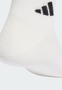 Calcetín deportivo blanco con un patrón de punto texturizado y un logotipo de marca negro en el lado, mostrando una parte superior acanalada.