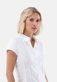 Weißes Kurzarmhemd mit kragenförmigem Ausschnitt, durchgehender Knopfleiste und subtiler Textur. Verfügt über vertikale Nähte und eine taillierte Passform.