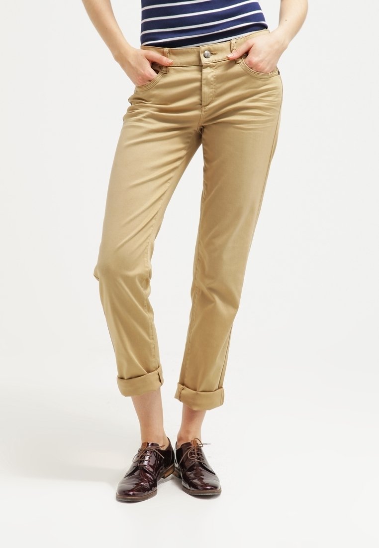 Světle béžové chino kalhoty s ohrnutými nohavicemi, vyrobené z hladké bavlněné látky. Kalhoty mají klasický střih, přední kapsy a zapínání na knoflík.
