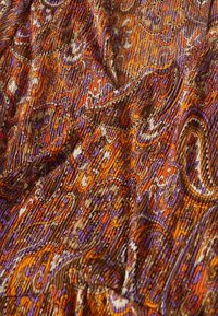 Monivärinen paisley-kangas, jossa on oranssin, violetin ja ruskean sävyjä, teksturoitu pinta ja monimutkainen kuviointi.