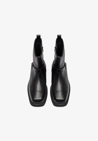 Botas de cuero negro hasta el tobillo con punta cuadrada, con un cierre lateral y una textura suave. Diseño minimalista sin patrones ni acentos visibles.
