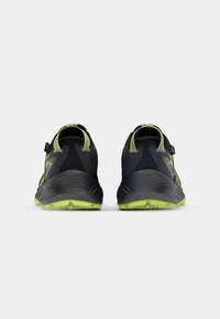 Black and green athletic shoes featuring a mesh upper, textured heel, and rugged sole with a distinctive tread pattern.