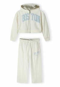 Cream-colored two-piece loungewear set featuring a zip-up hoodie with "BOSTON" print and matching pants with "USA 1967" graphic detail.