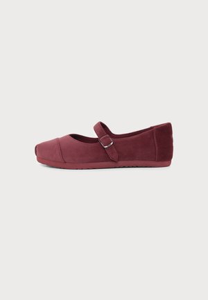 Chaussure plate unique bordeaux avec bout rond et bride ajustable avec boucle sur fond blanc uni.