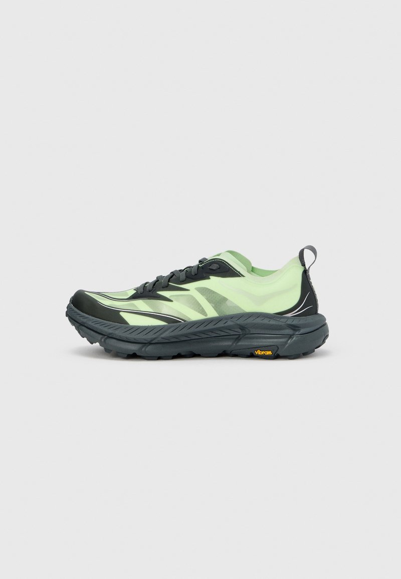 Tekaški čevelj z črno in svetlo zeleno zasnovo, s teksturirano podplatom in odsevnimi detajli, zasnovan za zmogljivost in stabilnost.