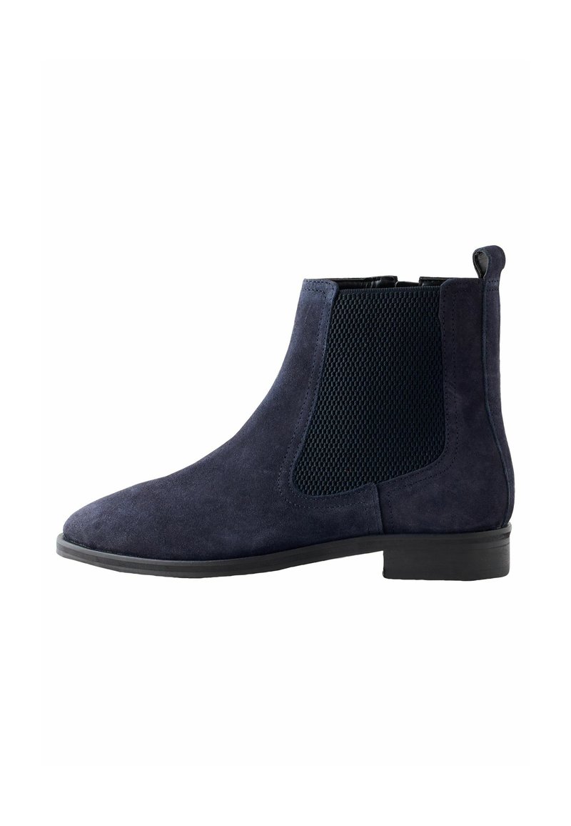 Botas Chelsea de ante azul marino con paneles elásticos laterales y una suela de goma negra. Presentan una puntera redondeada y una lengüeta en la parte posterior para facilitar el calzado.