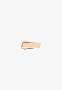 Tache de fond de teint beige clair avec une texture lisse et crémeuse sur un fond blanc uni.