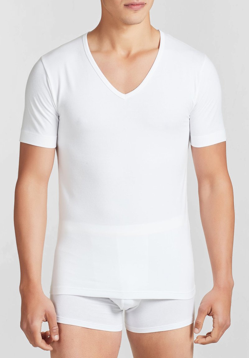 T-shirt bianca a maniche corte con scollo a V, realizzata in tessuto morbido, design aderente, texture liscia, abbinata a slip bianchi.