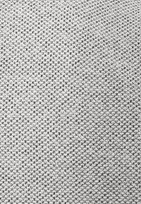 Texturerad grått tyg med ett vävt mönster, som har en blandning av ljusa och mörka trådar som skapar en subtil visuell djup.