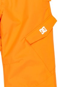 Oranžové nepremokavé nohavice vyrobené zo syntetického materiálu. Obsahujú klopovú vrecko a biele logo na boku. Hladká textúra, moderný dizajn.