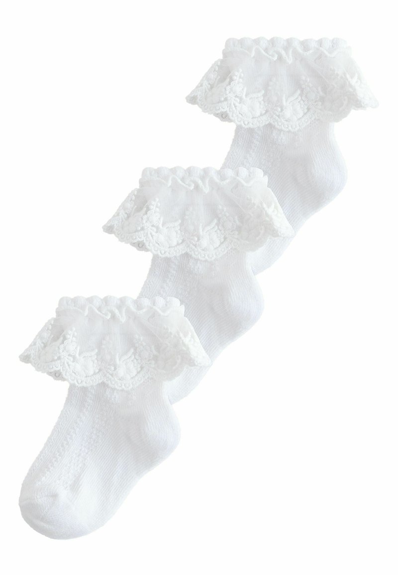 Trois chaussettes blanches pour bébé avec des volants délicats en dentelle autour de la cheville, disposées en chevauchement sur un fond blanc.