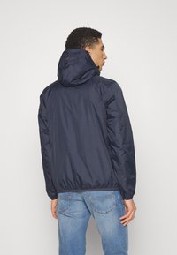 Marineblauer leichter Jacke mit Kapuze, elastischen Bündchen und gerafftem Saum, aus glattem, wasserabweisendem Material. Rückansicht dargestellt.