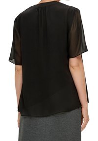 Blouse noire à manches courtes en tissu transparent, avec un design fluide, un col rond et un détail de pli au dos. Idéale pour les superpositions.