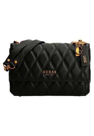 Black quilted leather crossbody bag with gold chain strap, gold "Guess EST 1981" logo, and decorative gold "G" and "1981" charms.