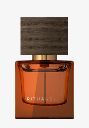 Square amber glass perfume bottle with a large dark wood-textured cap and the word Rituals on the front.