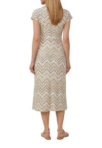 Abito midi a motivo chevron beige con maniche corte e tessuto lavorato a maglia. Sandali piatti indossati con l'abito.