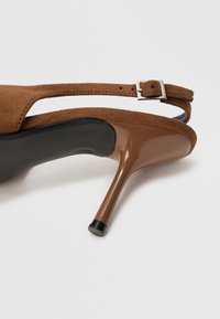Sandale cu toc înalt din piele întoarsă maro, cu un accent lucios maro pe toc, curea reglabilă pe gleznă și detaliu cu cataramă metalică.
